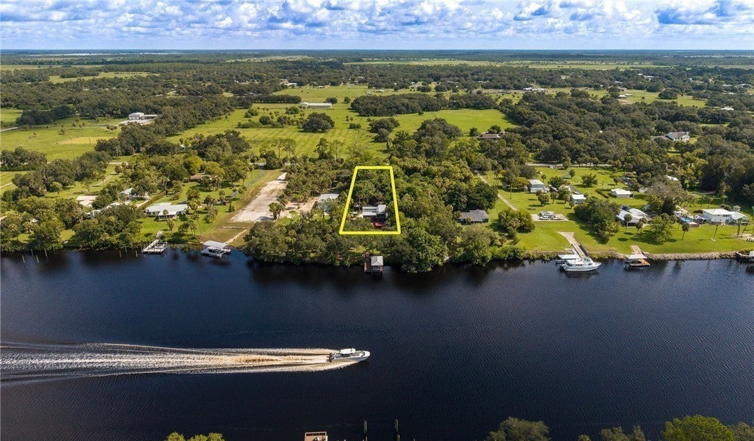 Aerial view of the riverfront property with a yellow illustrative parcel outline