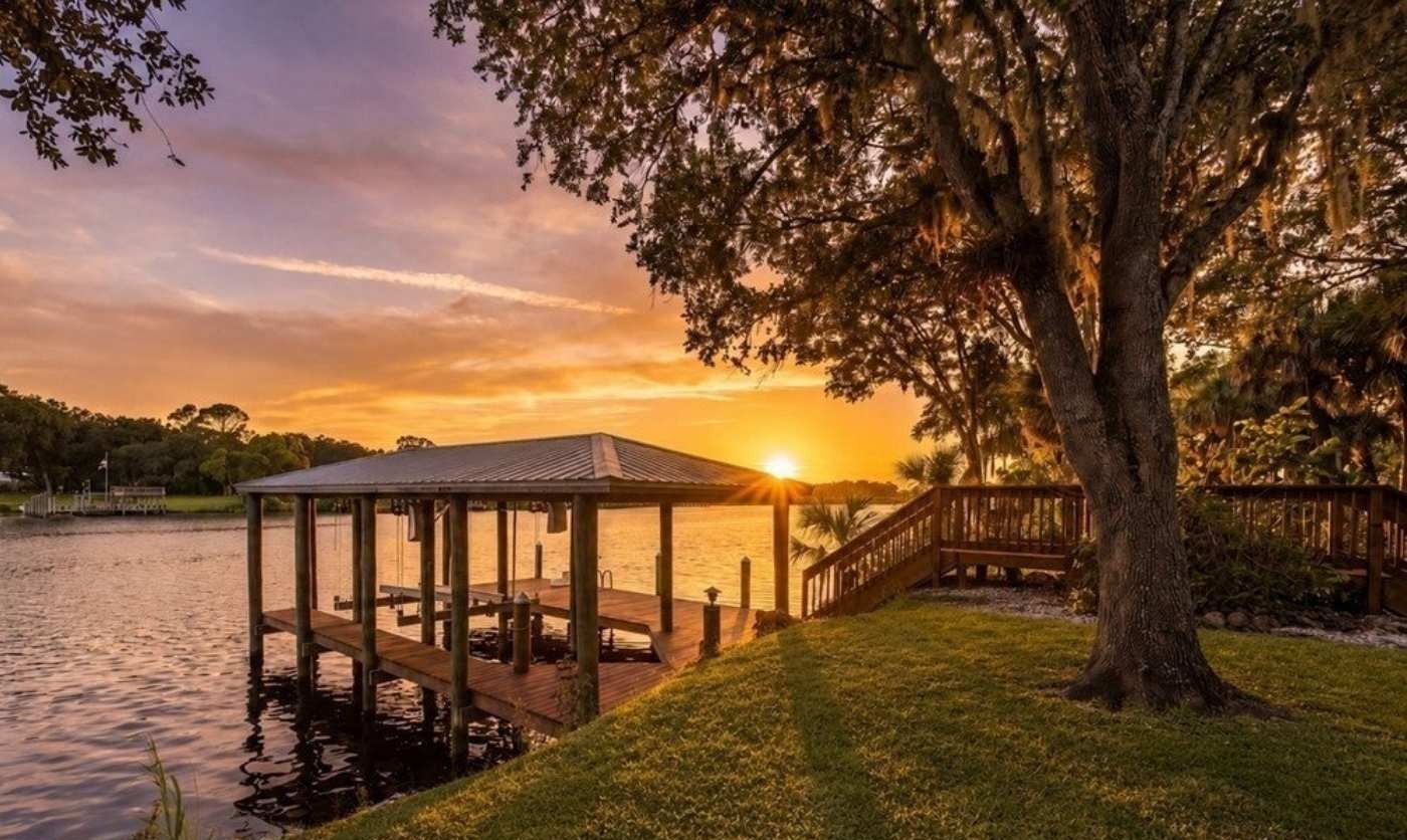 Covered boathouse and riverfront lawn at sunset