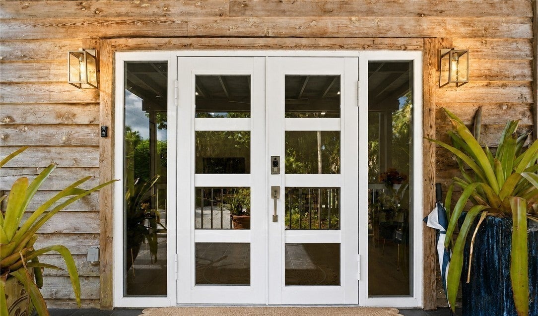White double doors framed by the home's weathered wood exterior