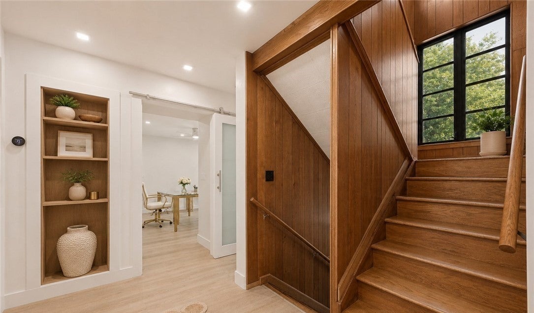 Wood staircase, paneled walls, and black-framed window