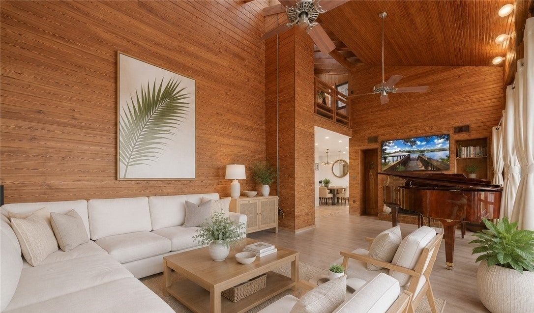 Wood-paneled living room with white seating and grand piano