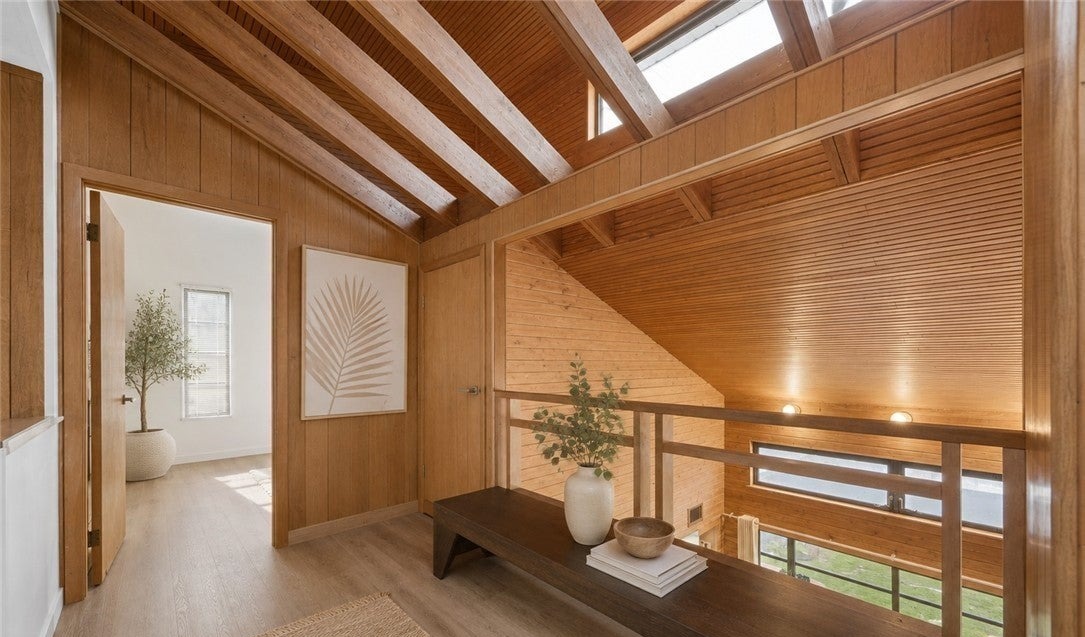 Upper landing framed by warm wood walls and vaulted ceiling beams