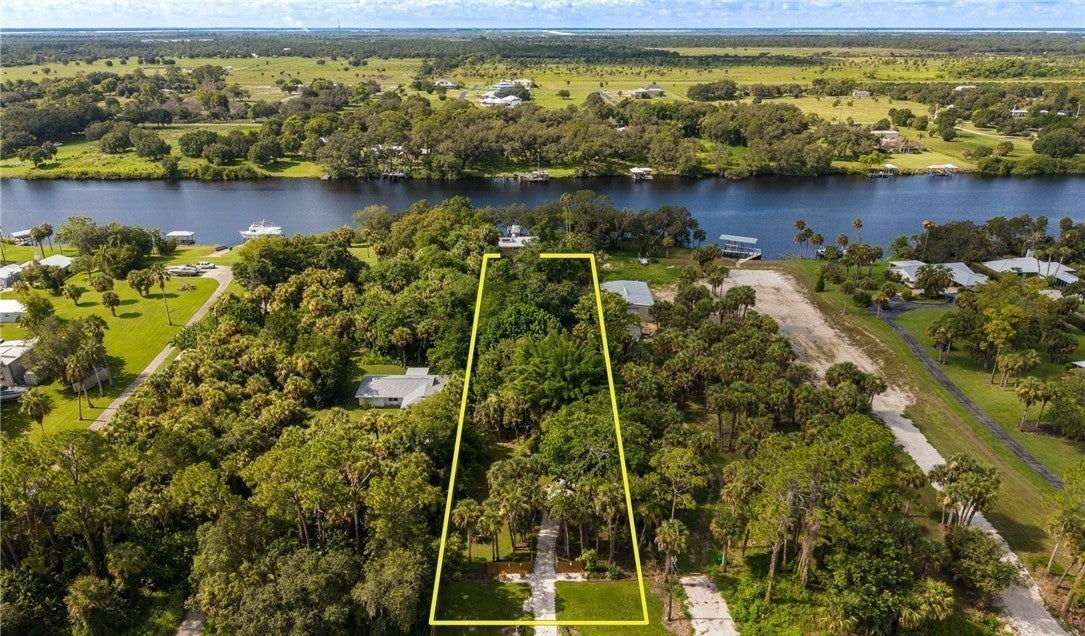 Aerial photograph of the wooded riverfront parcel with a yellow illustrative boundary outline